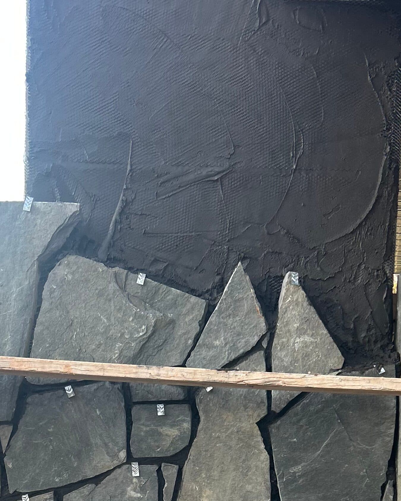 Stone veneer going onto a chimney chase over the scratch coat