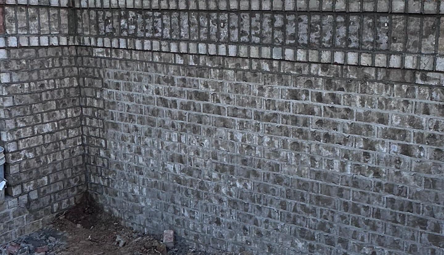 Esquina de un muro de ladrillo terminado con su hilada de remate