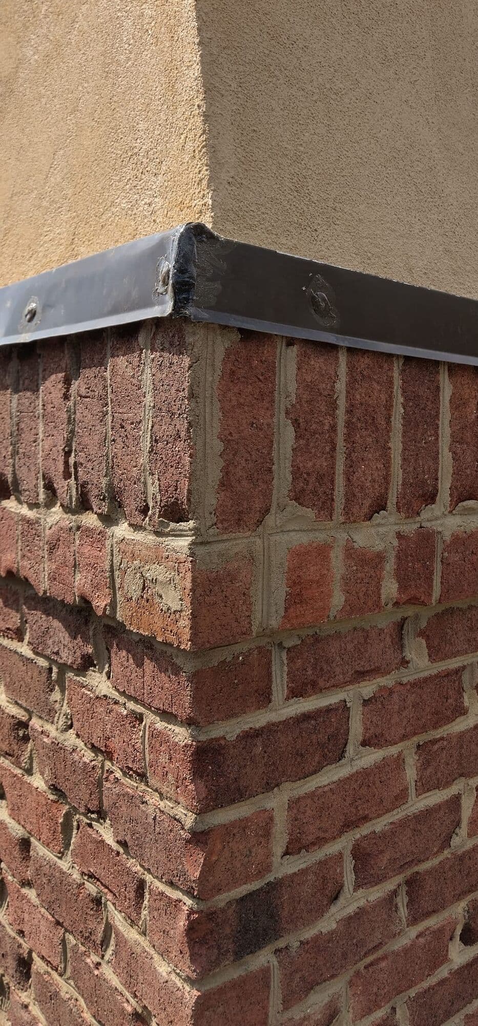 New metal drip cap over the brick courses at the corner of the chase