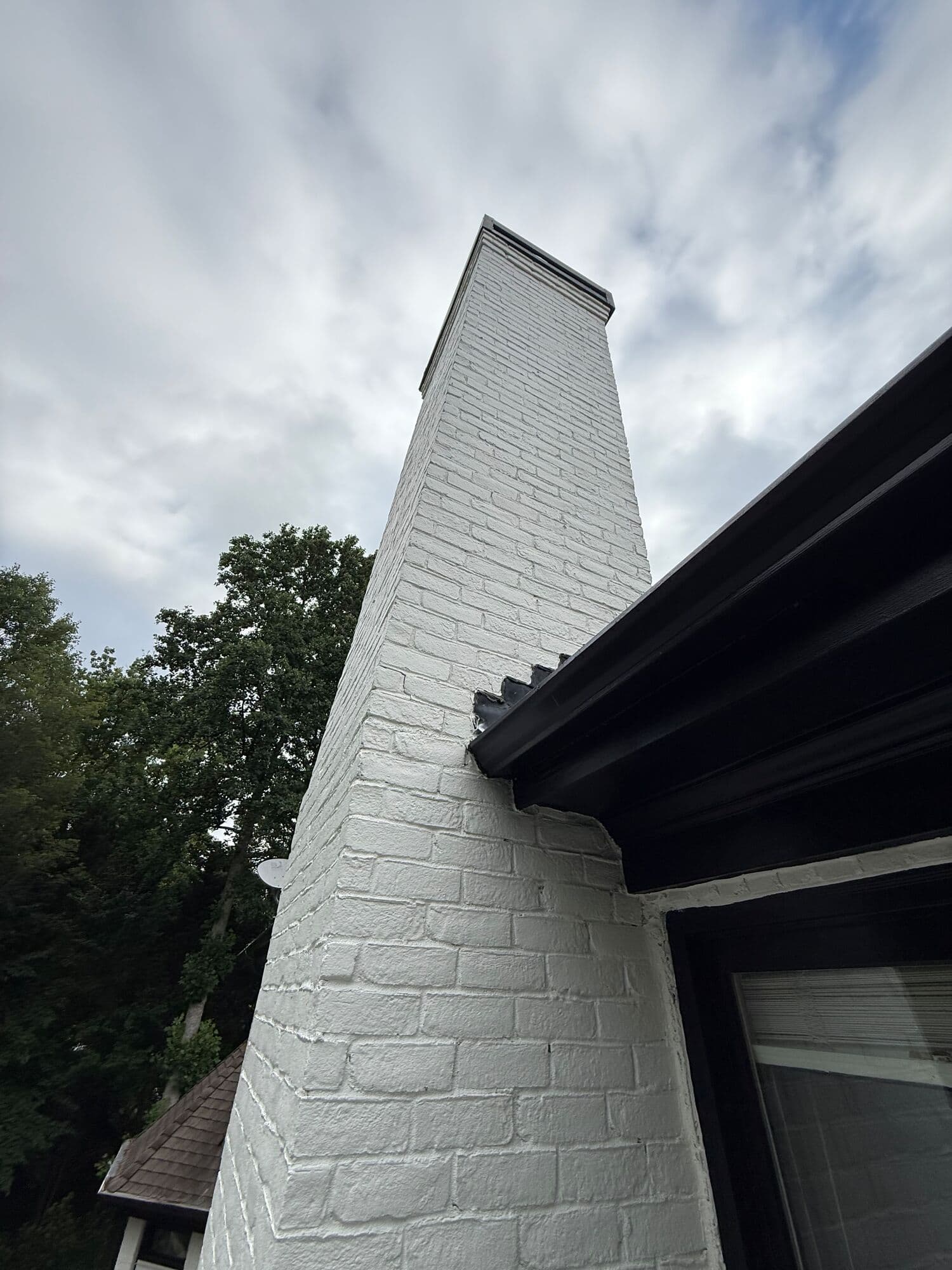 White painted brick chimney pulling away from the eave, before it came down
