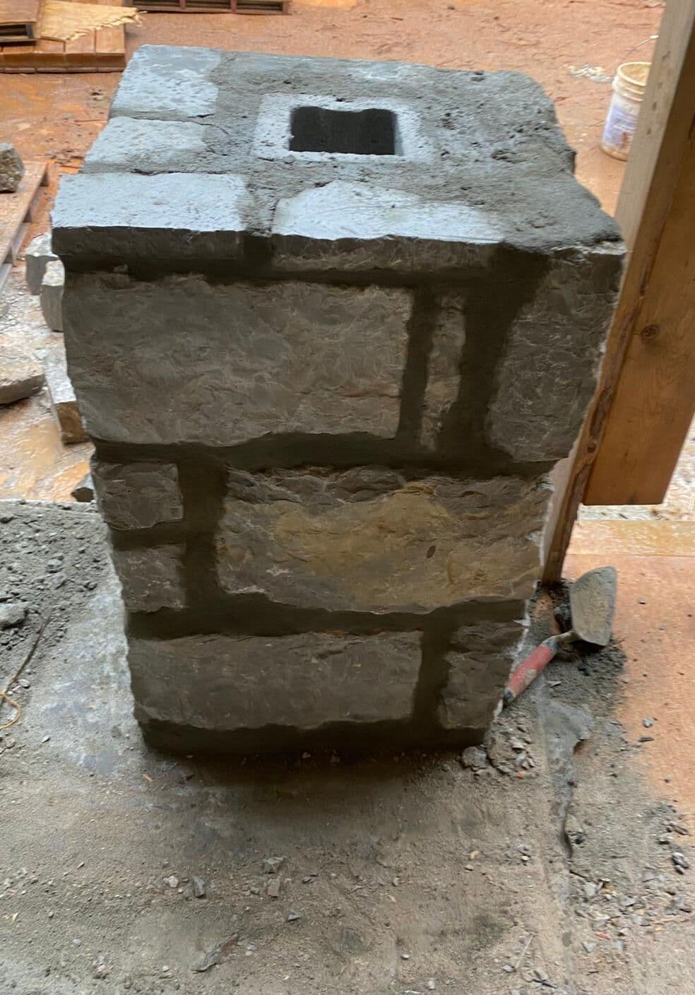 Base de columna de piedra con recortes y mortero sobre la losa a su alrededor