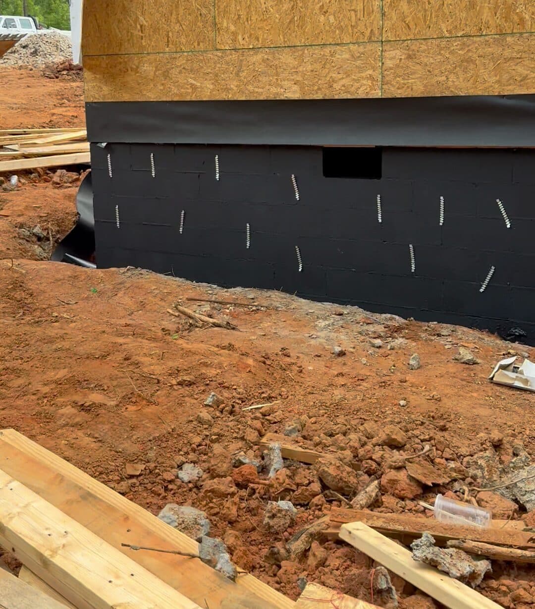 Black waterproof coating across the block foundation, with brick ties set in rows