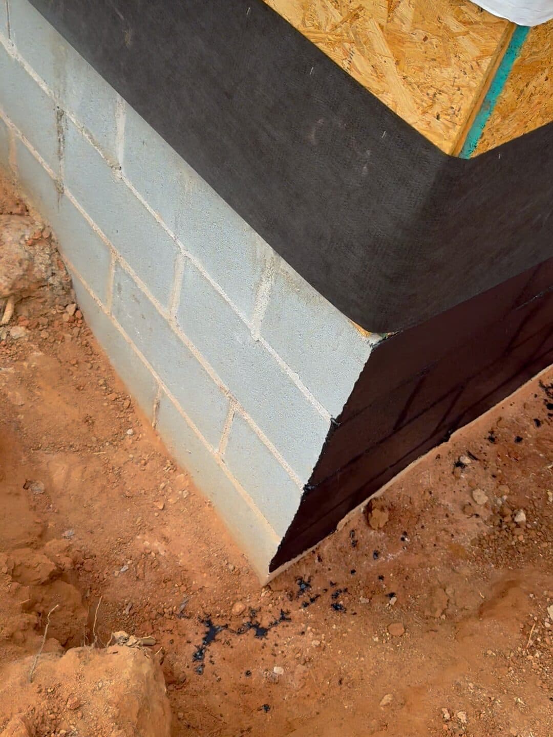 Recubrimiento impermeable negro traslapado sobre la esquina del muro de block