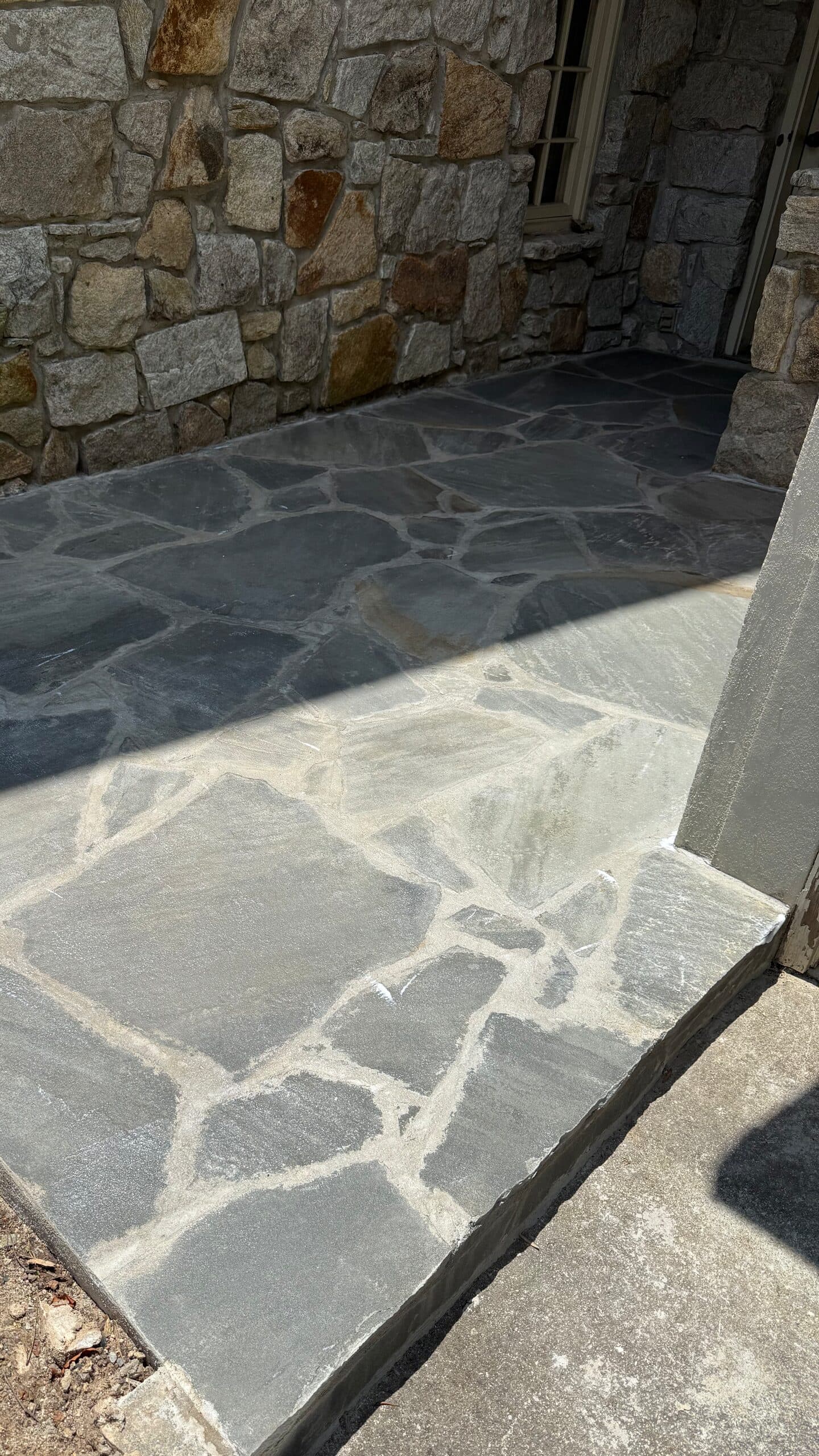 Flagstone landing set in mortar against a fieldstone wall